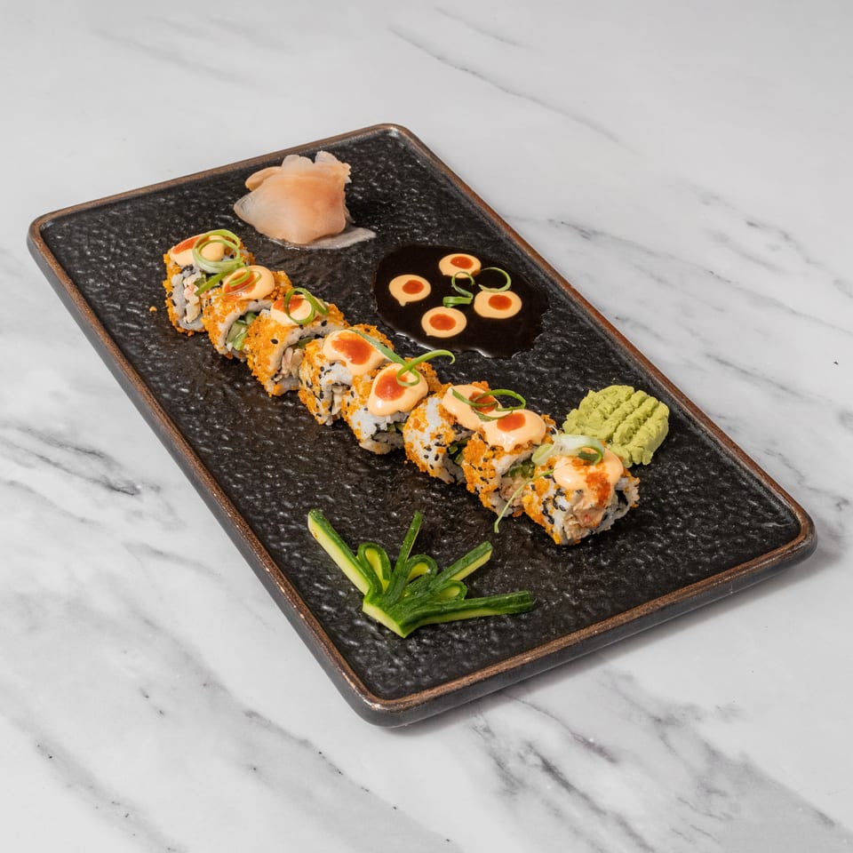 Sushi rolls with orange roe, sauce, green onions, pickled ginger, wasabi, and soy sauce.